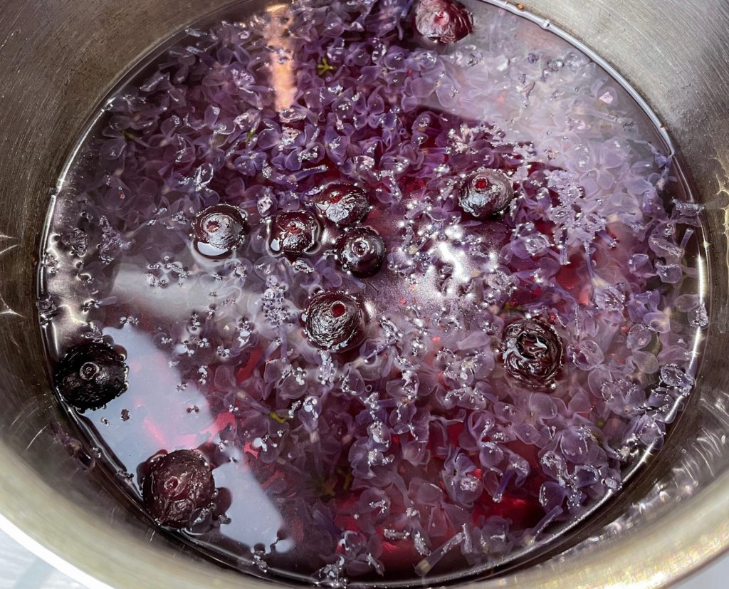 Lilacs, blueberries and sugar simmering in a pot