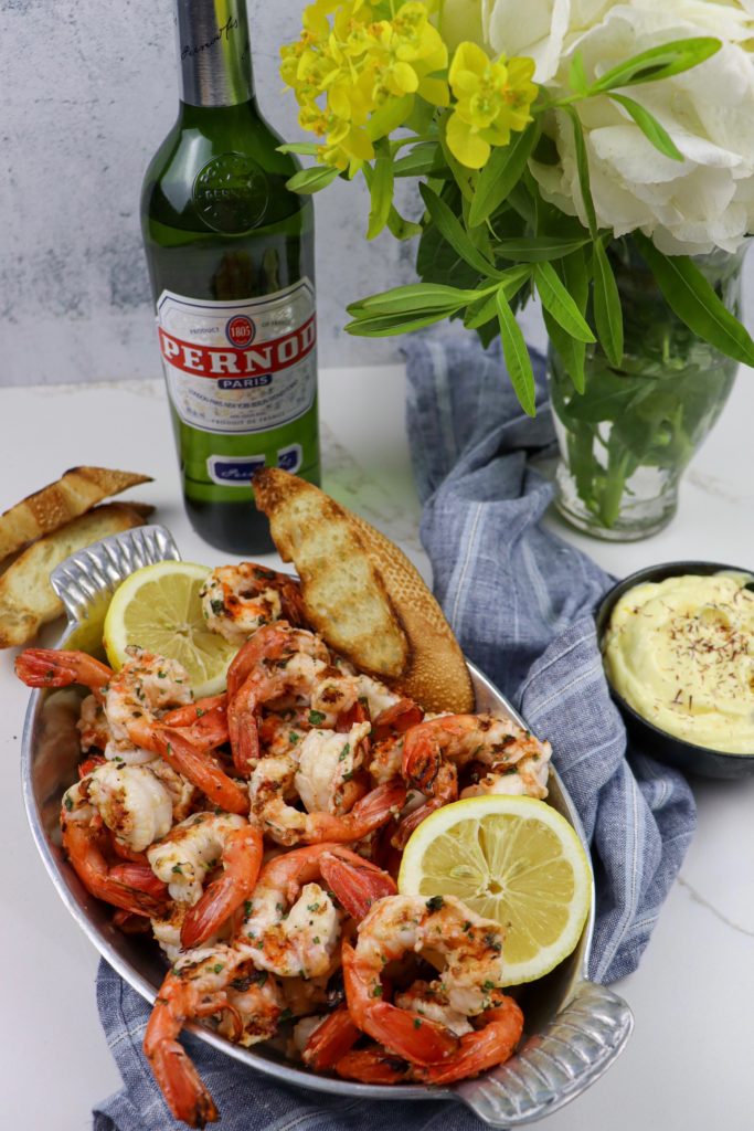 Grilled spot prawns next to saffron aioli and a bottle of Pernod for the prawn marinade