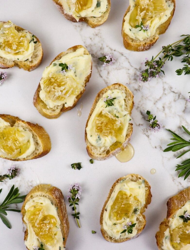 Slices of baguette topped with whipped brie with herbs and honeycomb