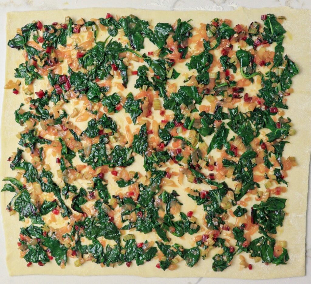 Swiss chard filling spread out on puff pastry sheet
