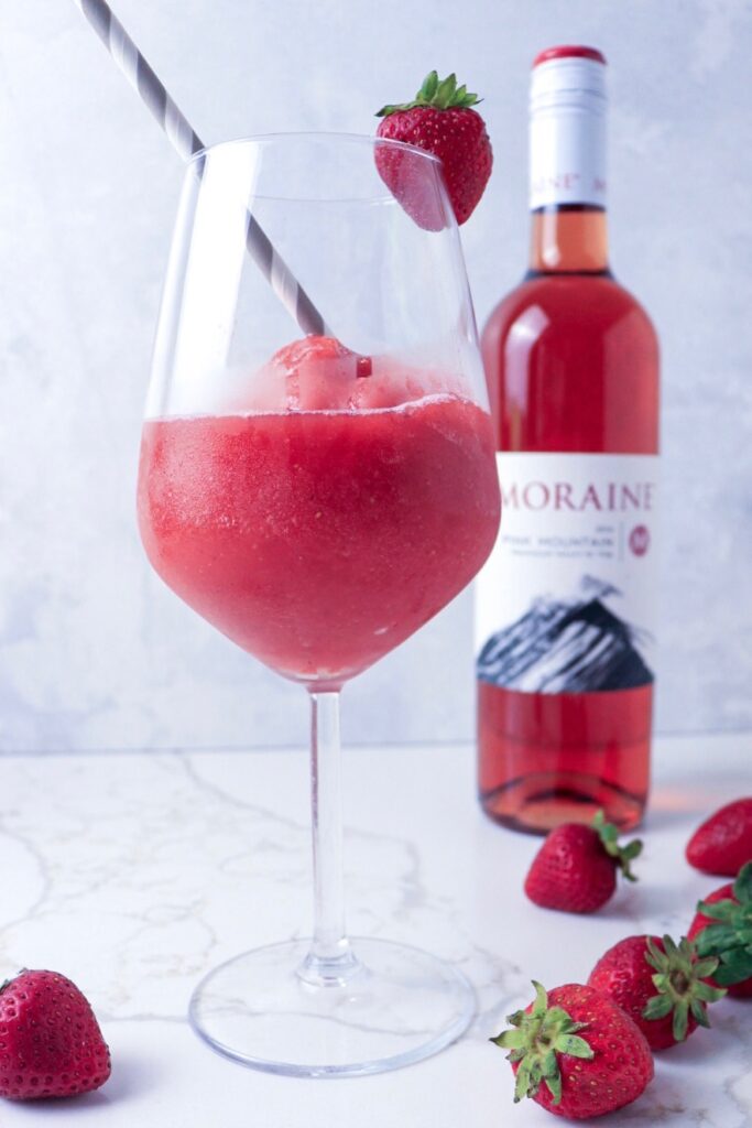 Glass of strawberry elderflower frosé and bottle of rosé