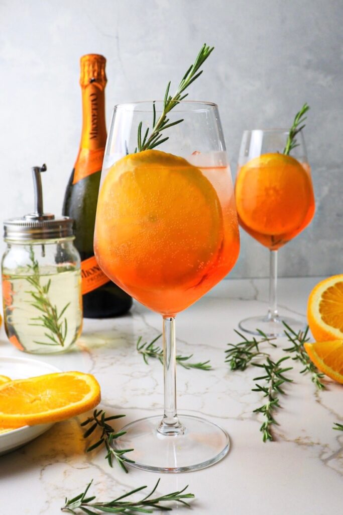 Two glasses of rosemary aperol spritz with rosemary simple syrup