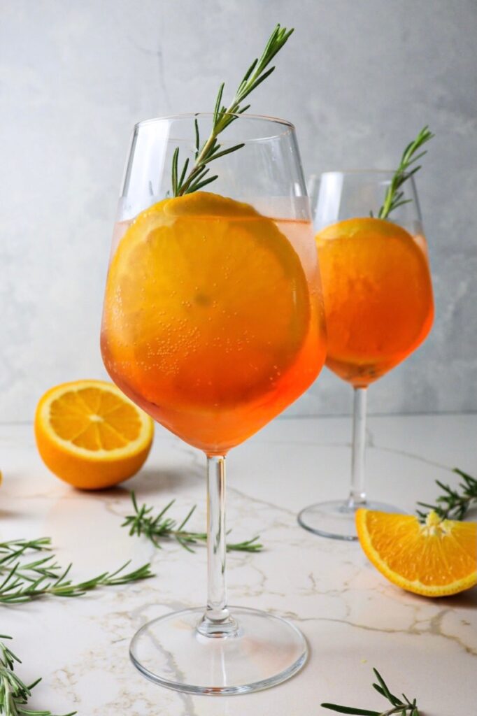 Two glasses of aperol spritz with fresh rosemary