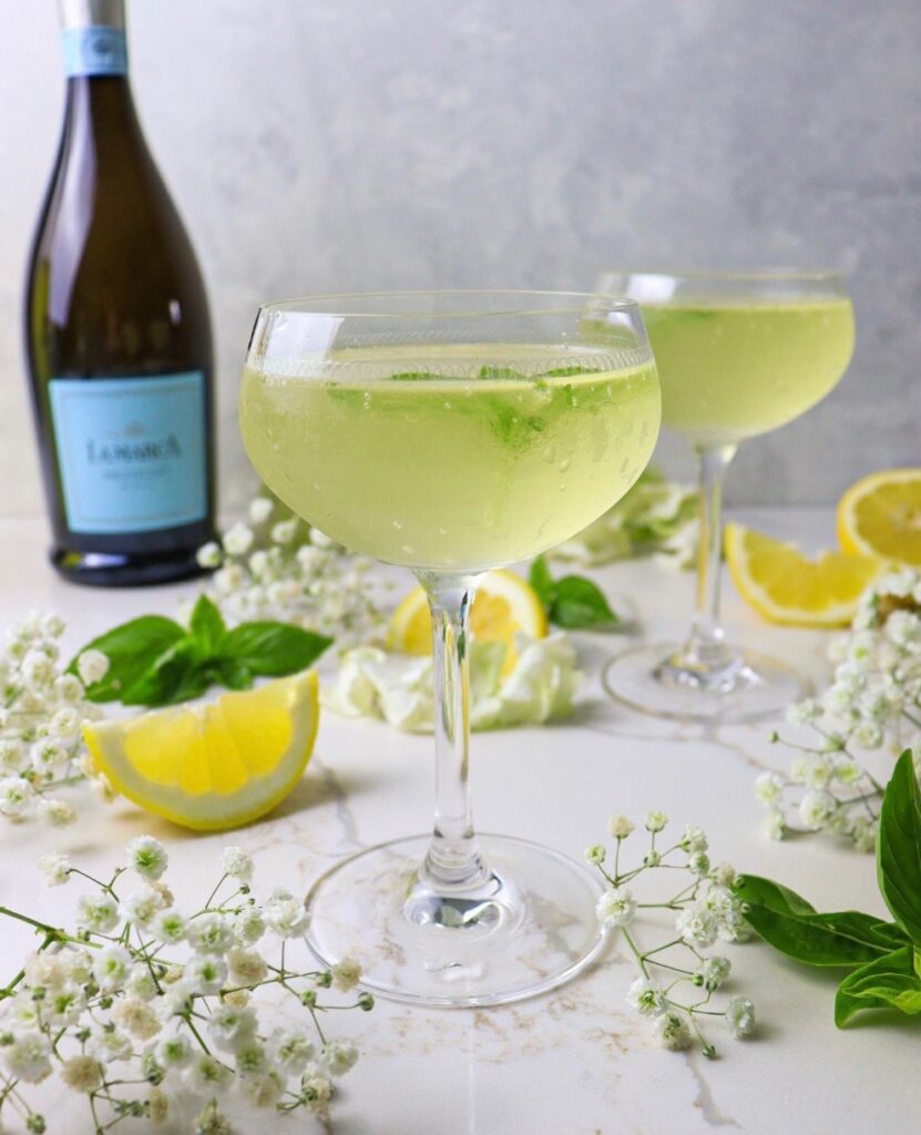 Limoncello basil cocktail with bottle of sparkling wine